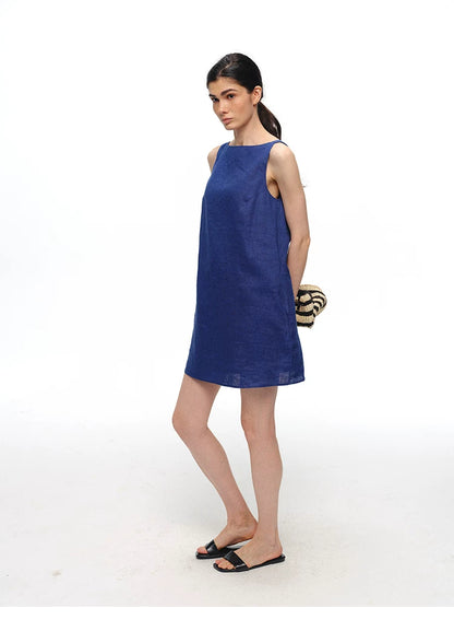 Royal blue linen shift dress styled with woven bag, side view