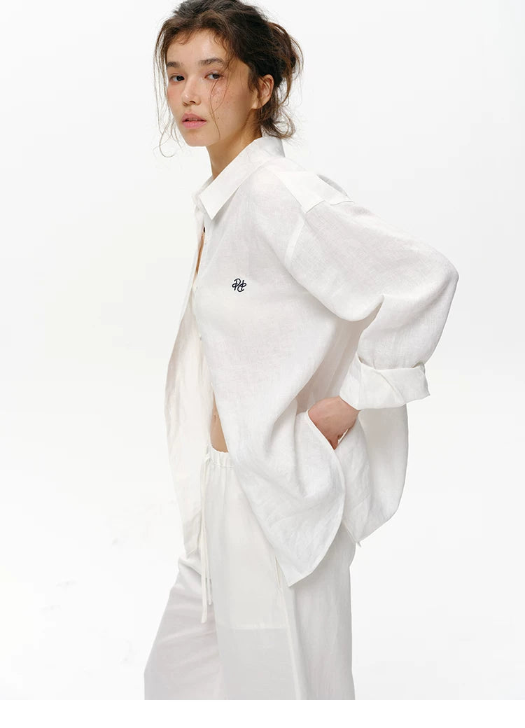 Woman wearing white embroidered linen shirt, side profile view