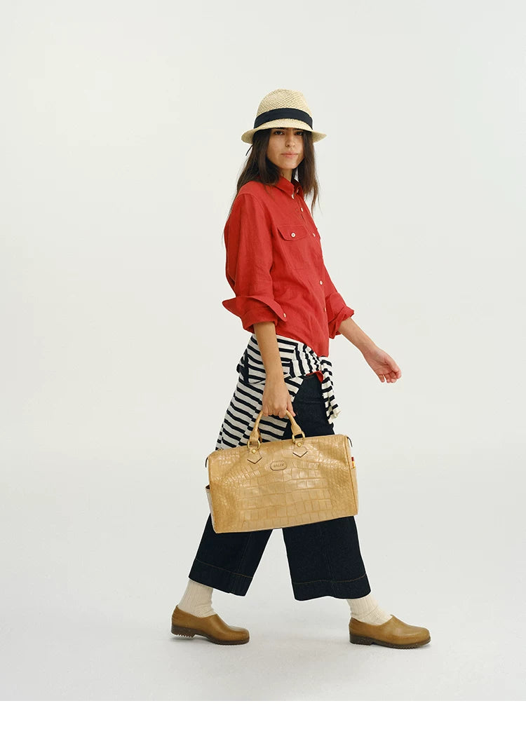 Side profile of woman walking in red linen utility shirt carrying tote bag