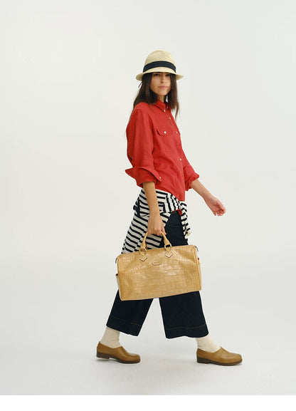 Side profile of woman walking in red linen utility shirt carrying tote bag