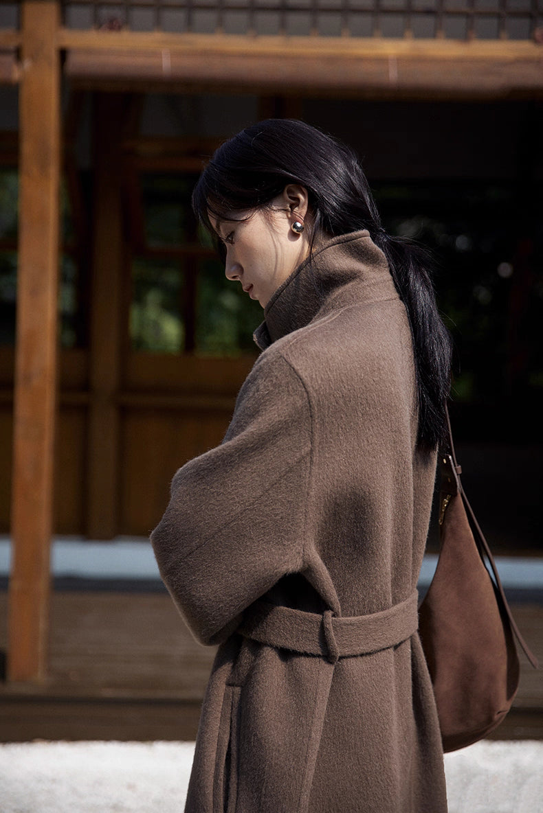 Side close-up of coffee brown llama wool coat showing raised collar and belt detail