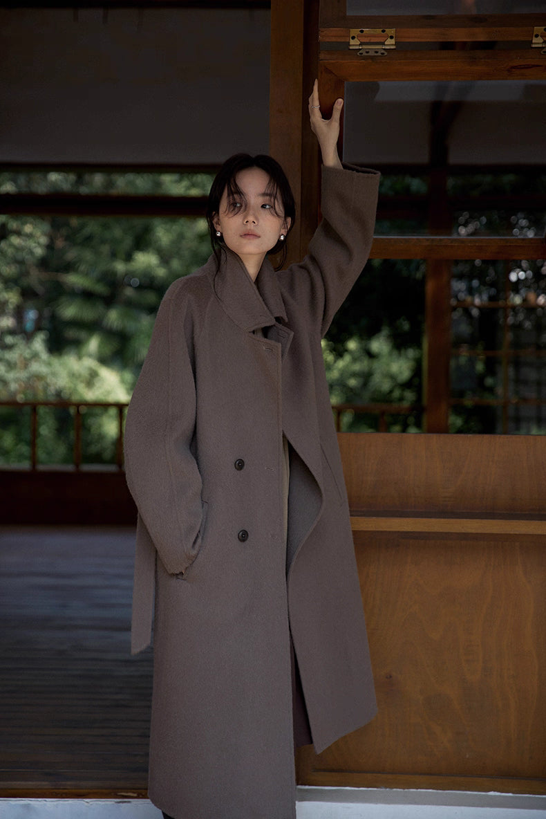 Full-length front view of long double-breasted llama wool coat with hands in pockets