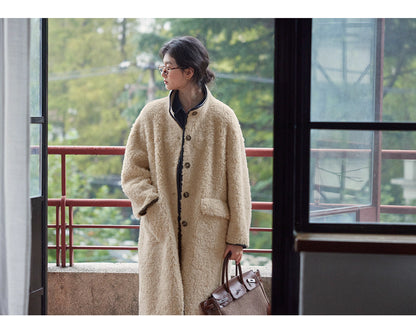 Full-length shot of woman wearing long beige wool shearling coat with brown leather bag.