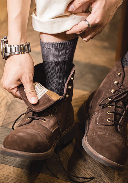 Close-up of Lucky Chunky Knit Socks in black as wearer adjusts brown boots highlighting textured knit and snug fit