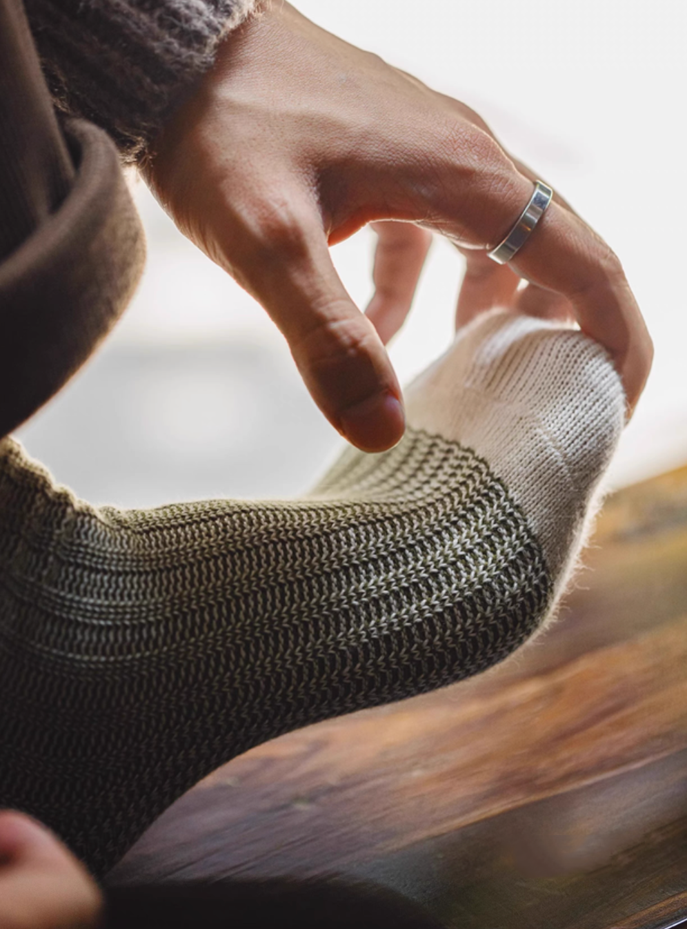 Close-up of Lucky Chunky Knit Socks in moss green stretched by hand demonstrating flexible knit fabric and soft cotton blend