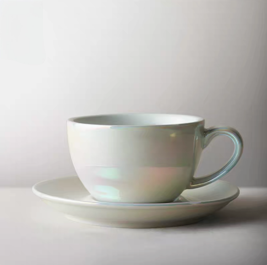 Luminous iridescent white ceramic coffee cup and saucer shown in clean minimal product view with soft reflective glaze