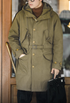 M47 Heritage Explorer Parka Coat in military green worn by model front view showing belted waist, oversized patch pockets, and button front design