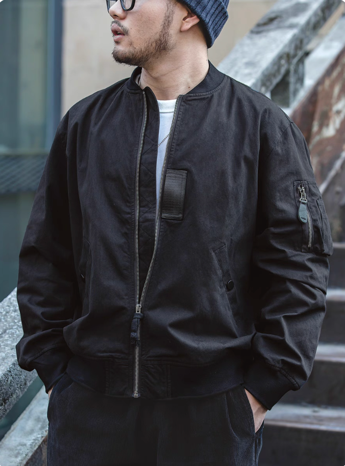 Men wearing black MA-1 bomber jacket with zip pocket and ribbed cuffs, urban casual streetwear style