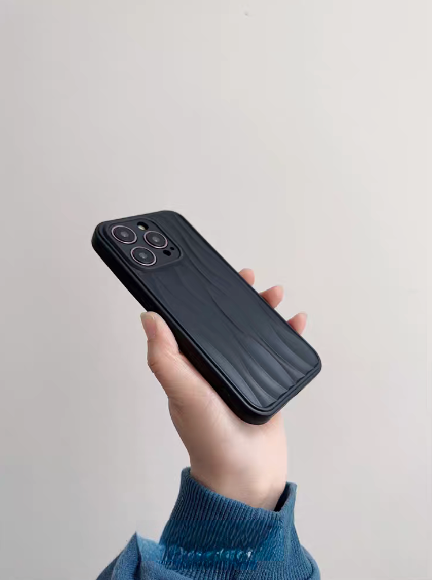 Matte black wave phone case held at an angle highlighting slim profile and smooth 3D wave texture