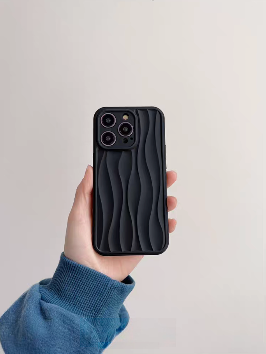 Matte black wave phone case held in hand showing 3D textured surface and raised camera protection