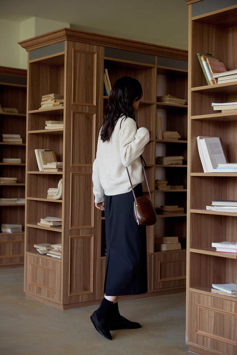 Mist white merino wool sweater back view near bookshelf highlighting clean lines and timeless silhouette