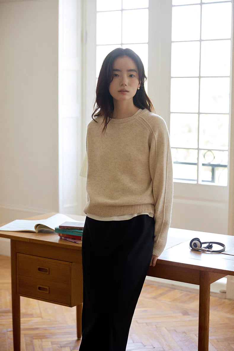 Mist white merino wool sweater styled standing by window with soft daylight showing relaxed fit and clean silhouette
