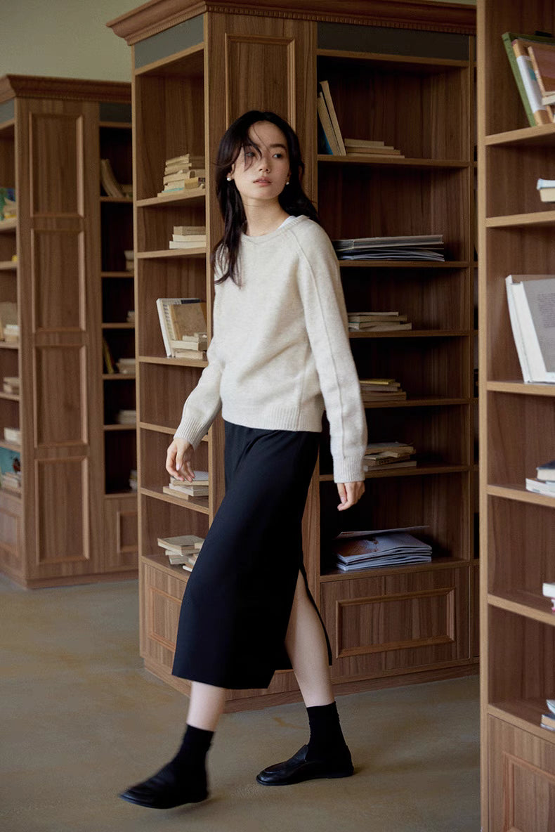 Mist white merino wool sweater worn while walking past wooden bookshelves showcasing straight fit and everyday styling