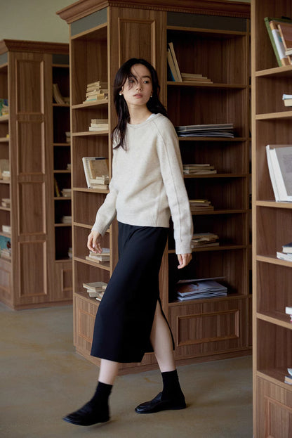 Mist white merino wool sweater worn while walking past wooden bookshelves showcasing straight fit and everyday styling