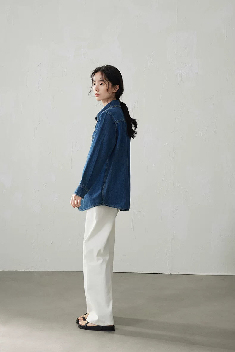 Side profile of a medium blue relaxed denim shirt covering the hips