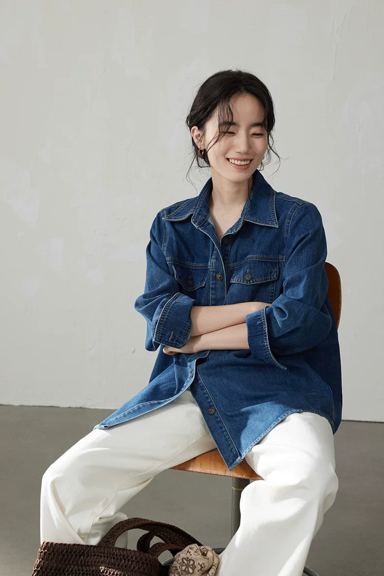 Model seated in a medium blue vintage denim shirt worn open over a tee