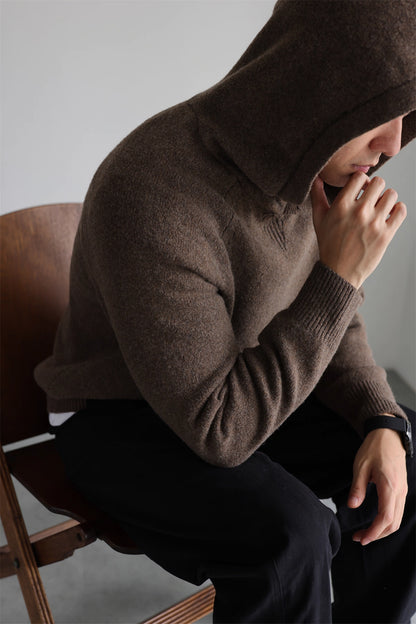 Coffee brown men’s knit hoodie with hood up, cozy wool-blend fabric, casual seated pose