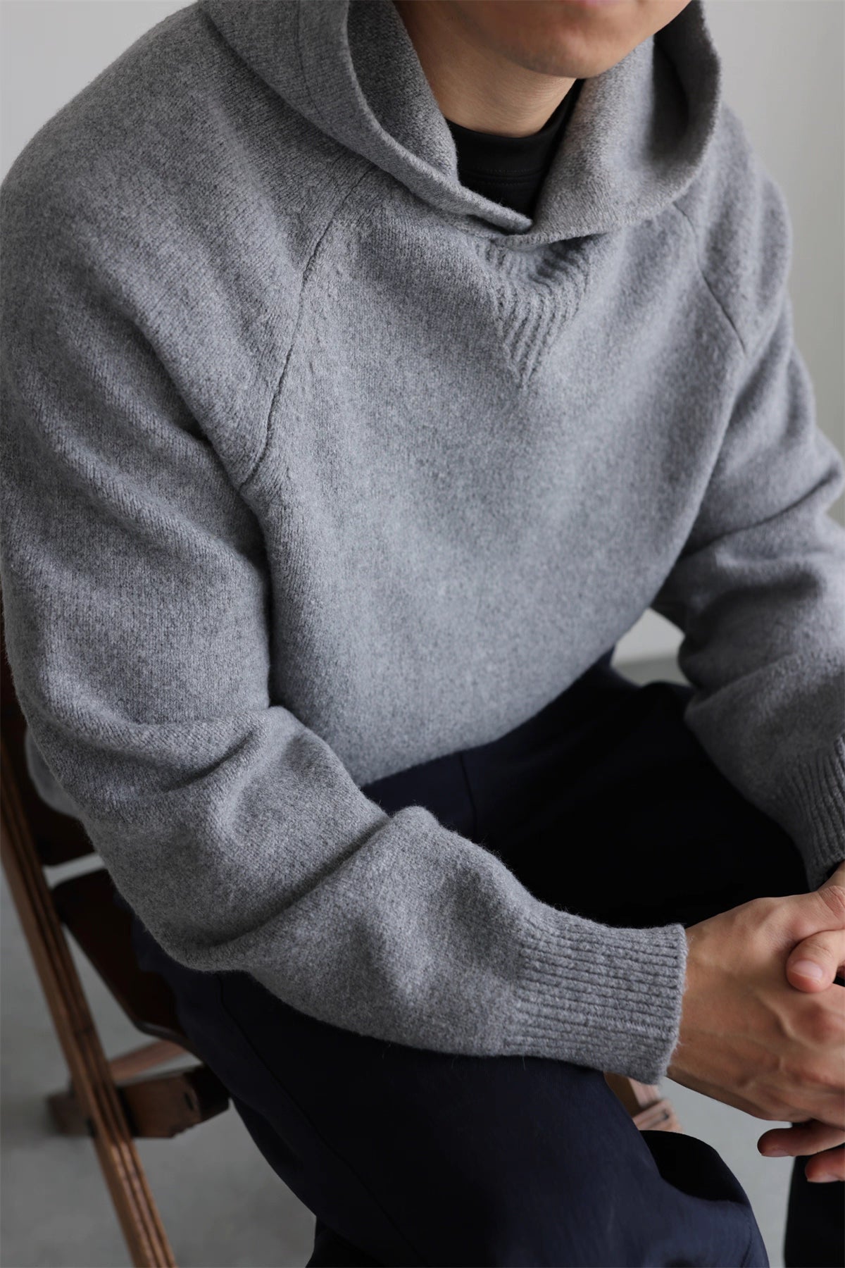 Model seated in gray wool-blend knit hoodie, casual winter look