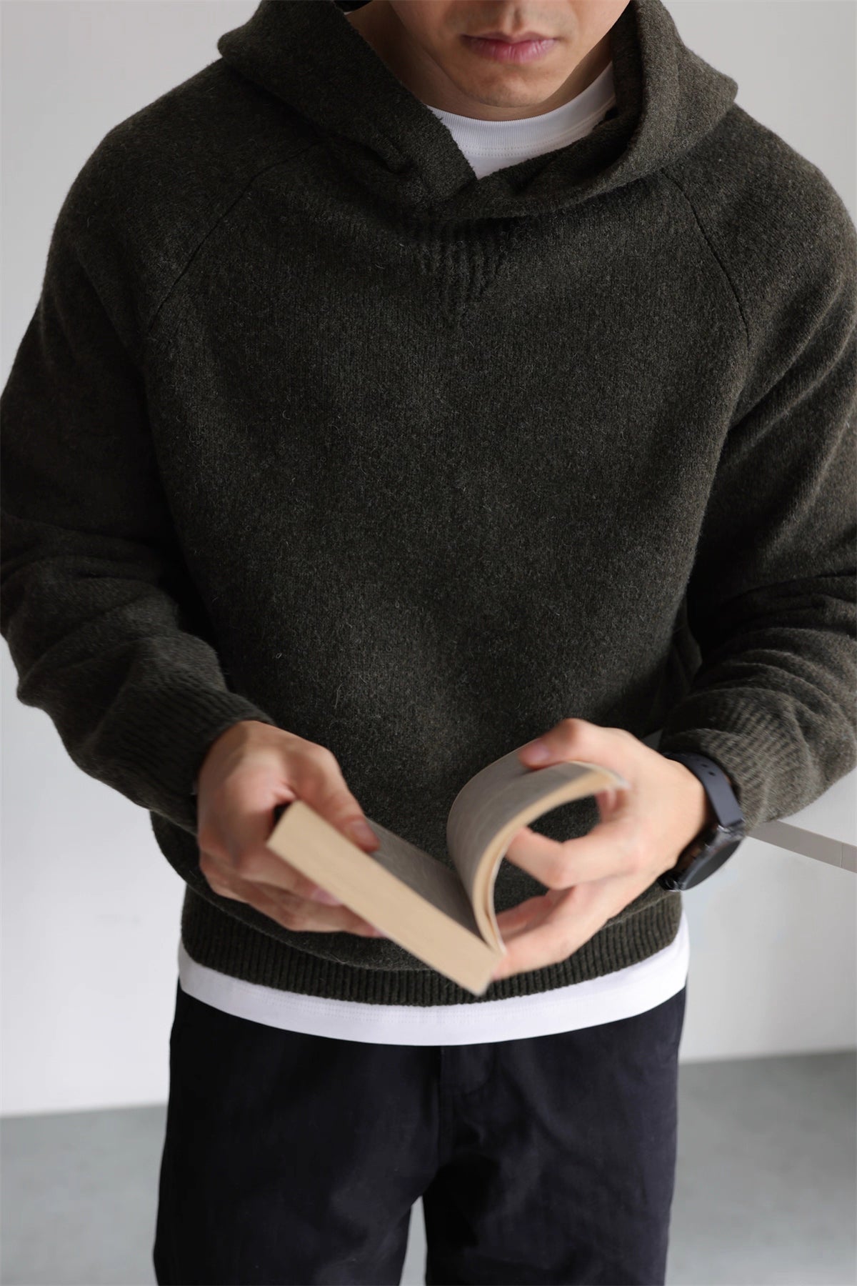 Model reading book wearing olive knit hoodie with brushed wool texture