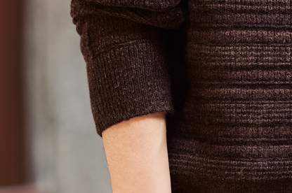 Sleeve cuff detail of brown textured Henley knit sweater with ribbed elastic hem.