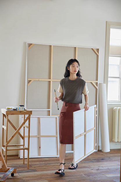 Model wearing Cool Black Tea knit top styled with skirt in art studio, showcasing textured knit pattern and elegant everyday outfit