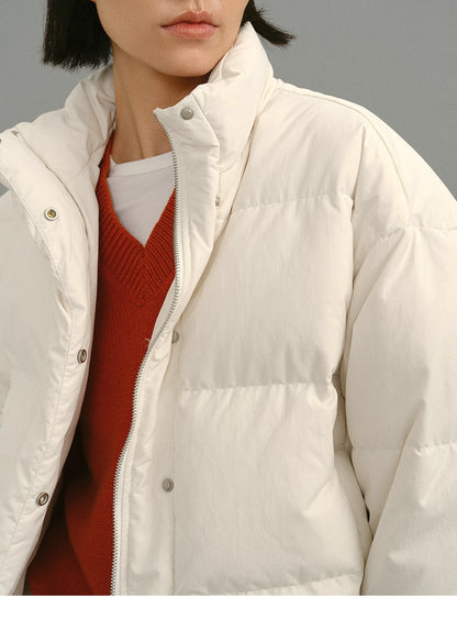 Close-up of the rust-orange Merino V-neck sweater layered under an oversized white puffer jacket, showing neckline and texture contrast.