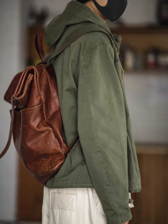 Army Green military deck jacket hoodie worn by model in side view, showing sleeve structure and styling with leather backpack