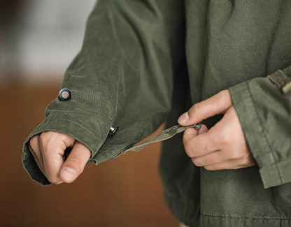 Close-up of Army Green military deck jacket hoodie sleeve, showing adjustable cuff strap and button detail