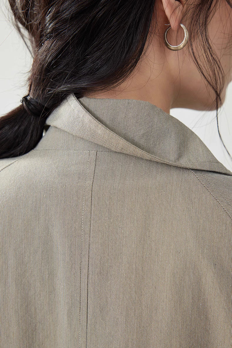 Close-up of collar and fine cotton twill texture of the light khaki gray minimalist trench coat.