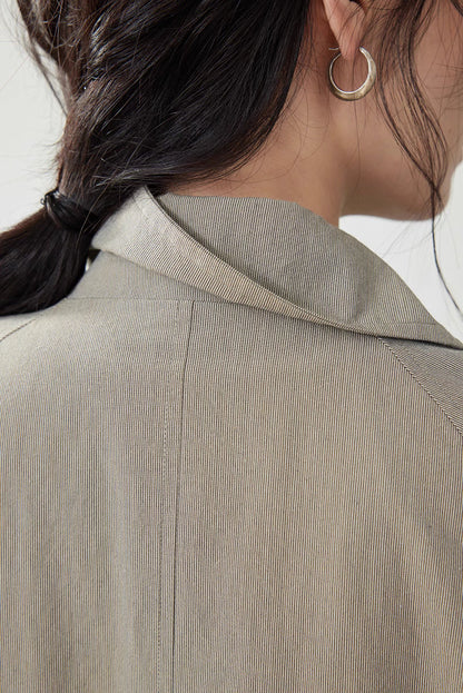 Close-up of collar and fine cotton twill texture of the light khaki gray minimalist trench coat.