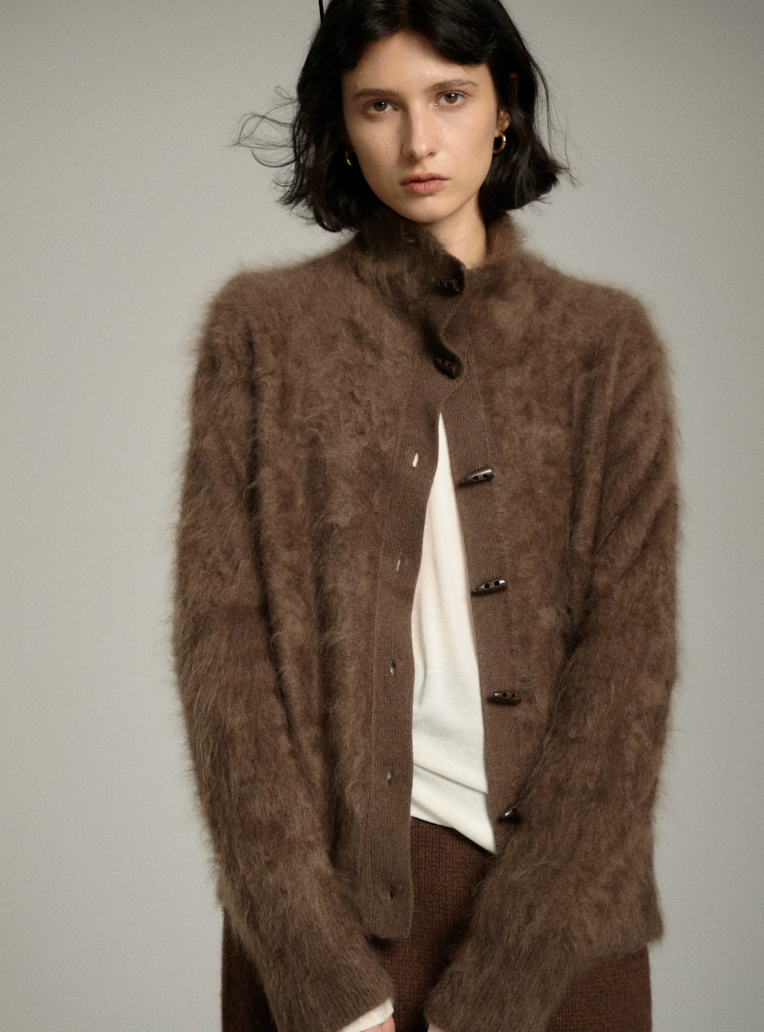 Mocha fuzzy cashmere cardigan worn partly unbuttoned over a white top, showing the ribbed placket