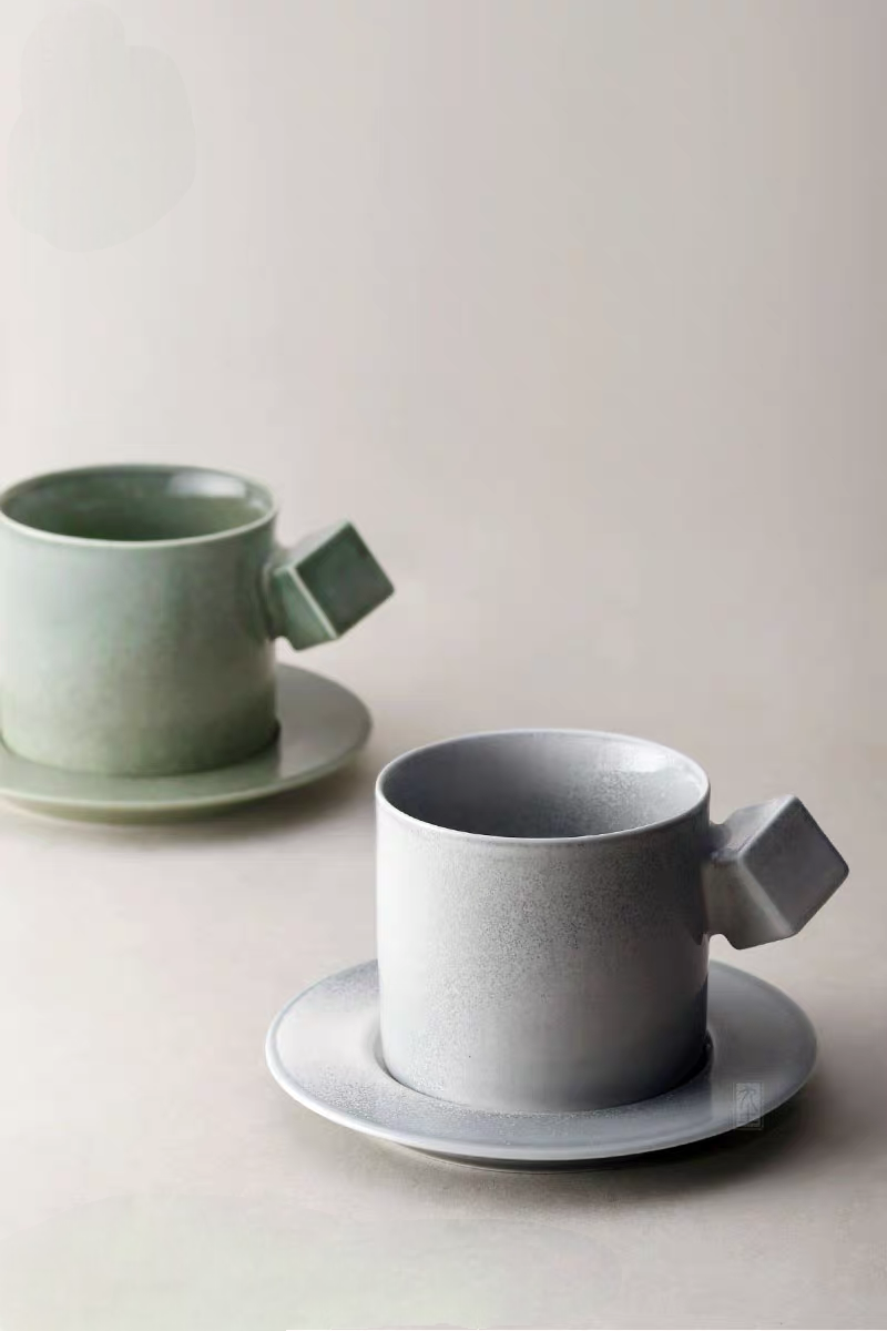 Modern Minimalist Ceramic Cup and Saucer Set in gray and green shown together on clean background with geometric square handles