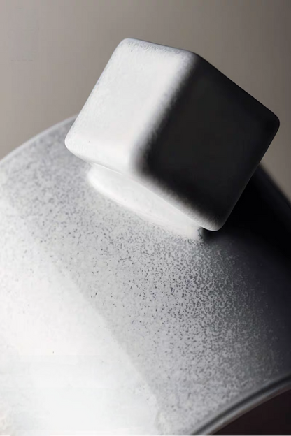 Close-up of gray ceramic cup square handle and saucer surface showing fine speckled texture and matte finish