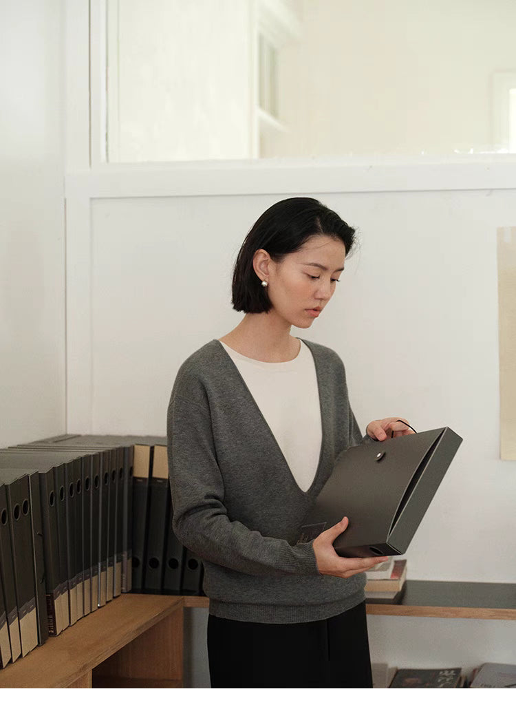 Front view of Dark Gray Modern V-Neck Relaxed Sweater with model holding box showing minimalist design and layering style
