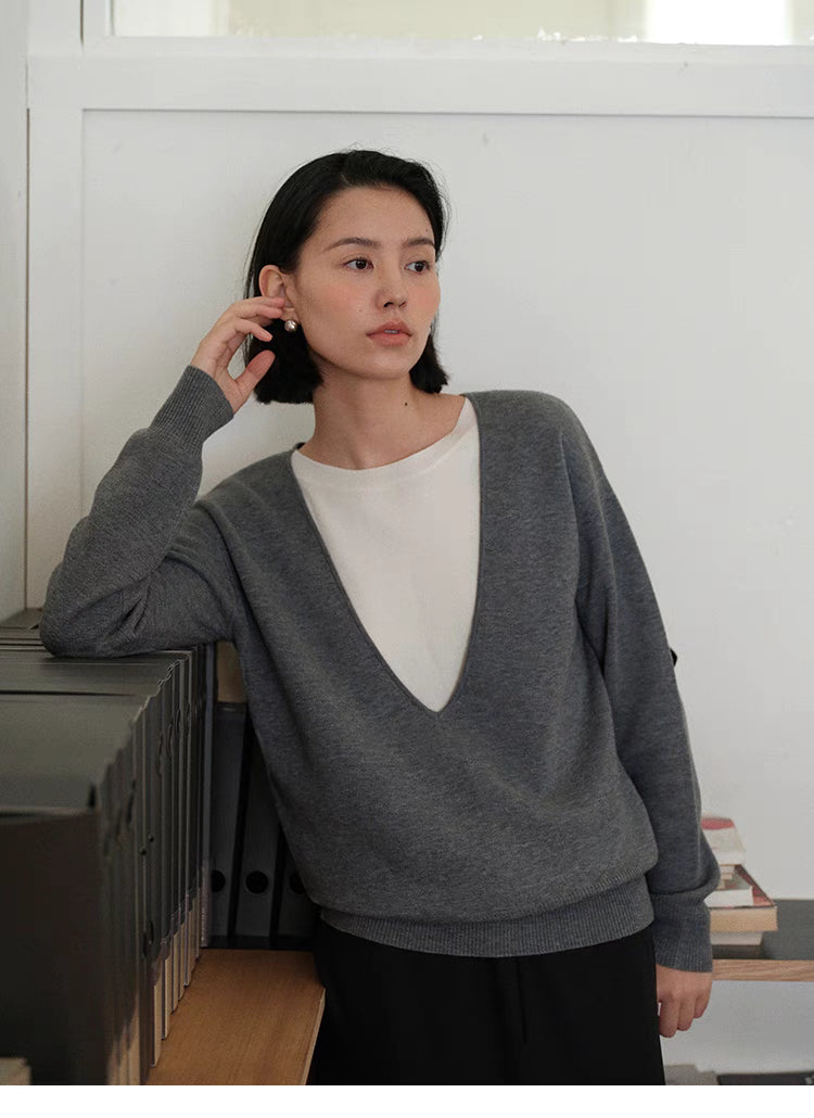 Modern V-Neck Relaxed Sweater in Dark Gray worn leaning on shelf highlighting relaxed fit and soft knit structure