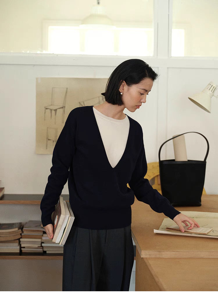 Modern V-Neck Relaxed Sweater in Navy Blue worn in office setting holding books showing layered look, relaxed fit and minimalist styling