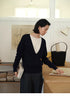 Modern V-Neck Relaxed Sweater in Navy Blue worn in office setting holding books showing layered look, relaxed fit and minimalist styling