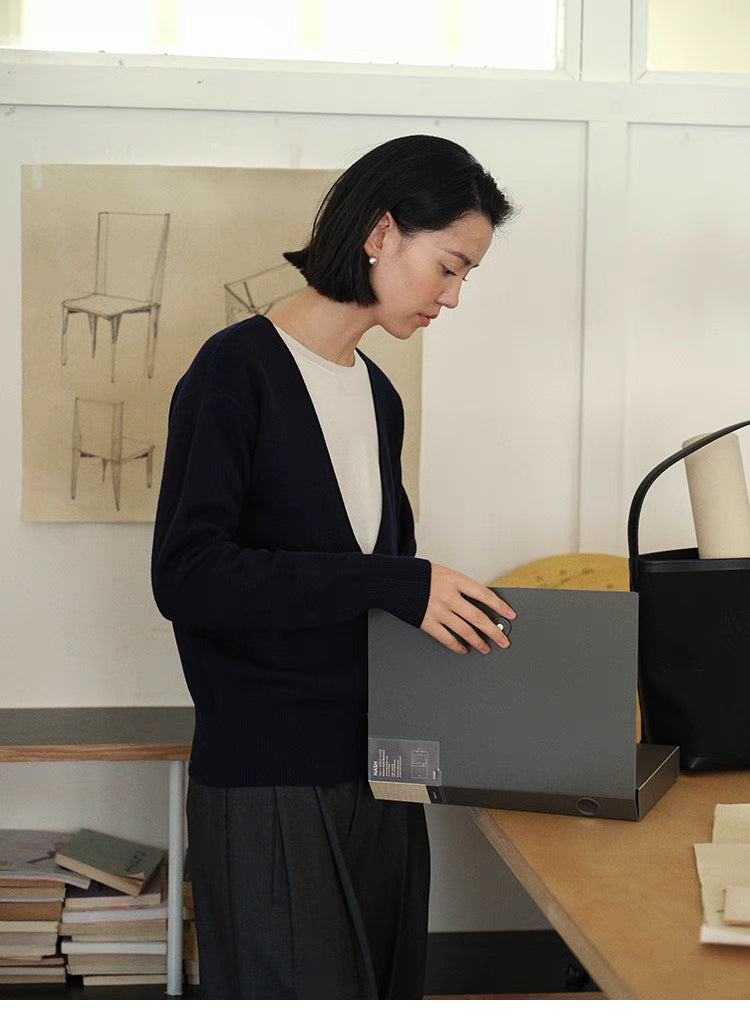 Side view of Navy Blue Modern V-Neck Relaxed Sweater with model holding storage box highlighting soft knit texture and relaxed silhouette