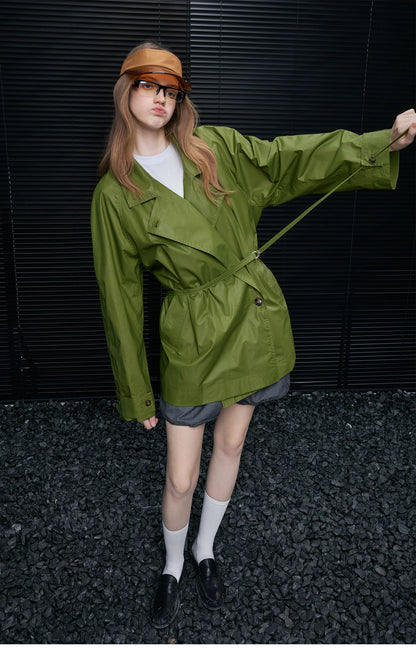 Moss Green trench jacket cinched with its D-ring belt over an asymmetric button front