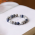 Mountain and sea gradient blue bracelet with white howlite, gray vein stone, and blue natural stone beads displayed on open book