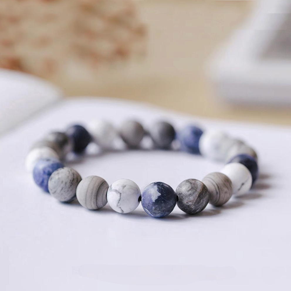 Close-up of gradient blue bracelet featuring white howlite, gray vein stone, and ocean blue beads in minimalist design