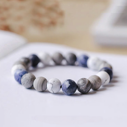 Close-up of gradient blue bracelet featuring white howlite, gray vein stone, and ocean blue beads in minimalist design