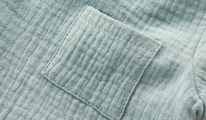 Close-up of light blue muslin baby romper chest pocket with textured cotton fabric