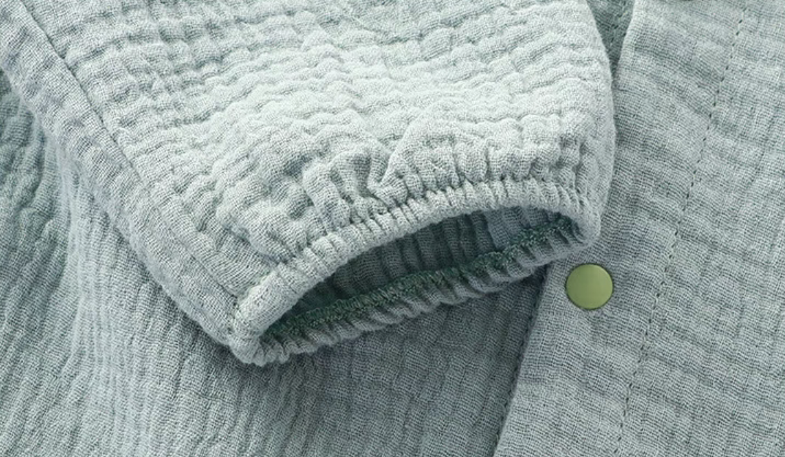 Close-up of light blue baby romper sleeve with elastic cuff and soft muslin texture