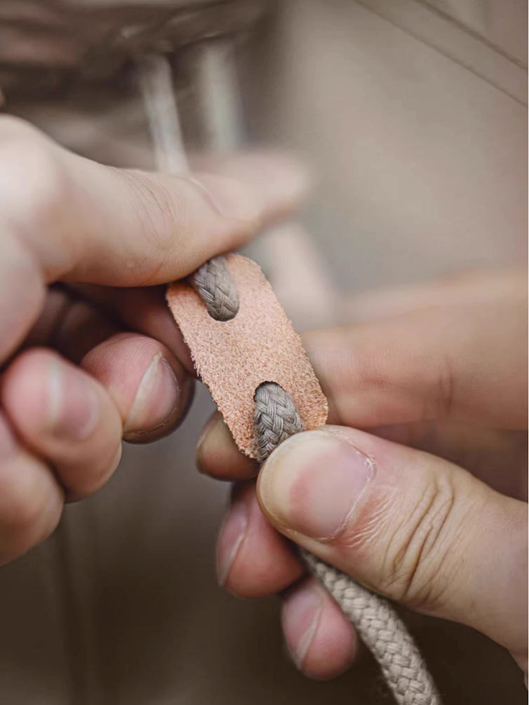 Close-up of genuine leather drawcord toggle on khaki parka hood.