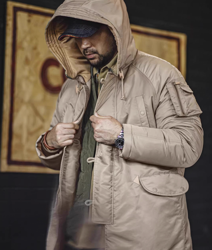 Model wearing hooded khaki N-3B parka with leather toggles visible.
