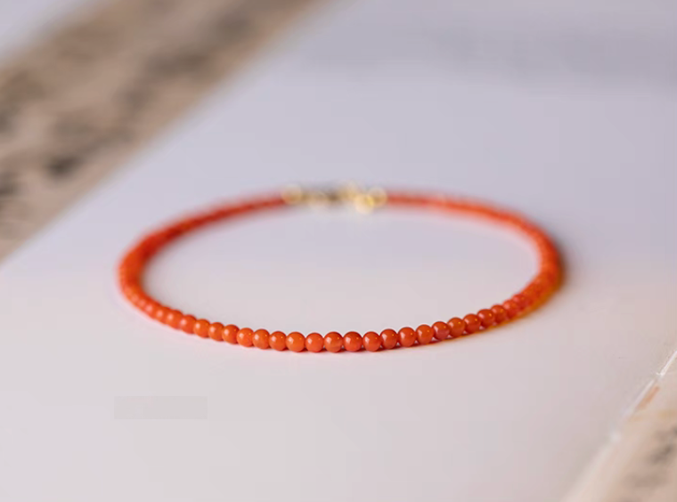 Natural red agate bracelet persimmon red beads full view flat lay on book surface