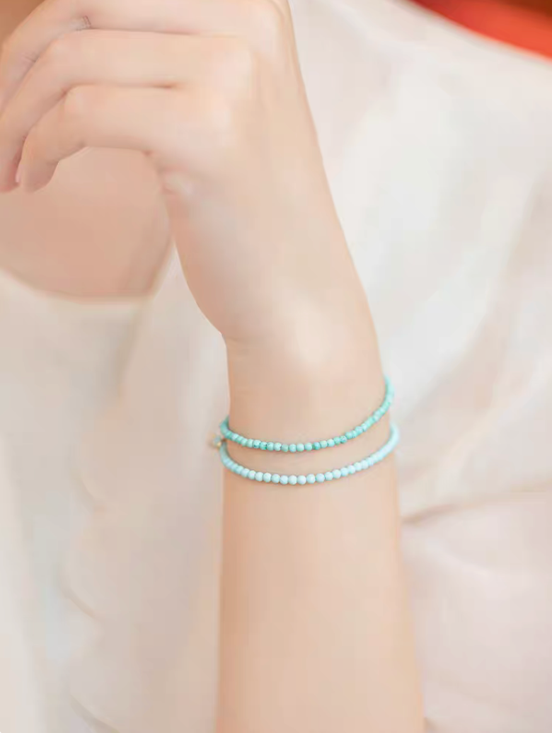 Natural turquoise bracelets worn as double wrap on wrist showing two bead sizes in soft lifestyle setting