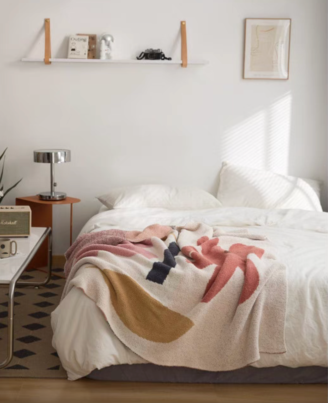 Floral letter chenille throw blanket draped across white bed in a bright minimalist bedroom