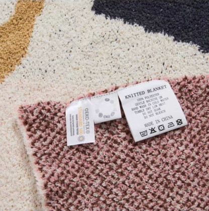 Close-up of floral letter chenille throw blanket showing textured knit surface and care label